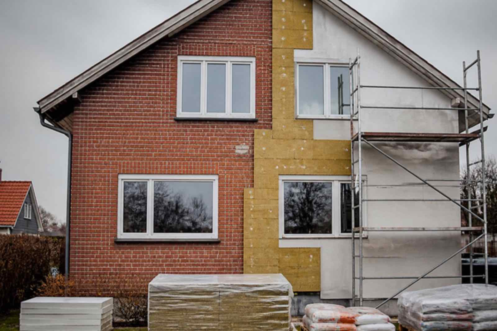 Murstensfacade under udvendig isolering, halvt isoleret og pudset