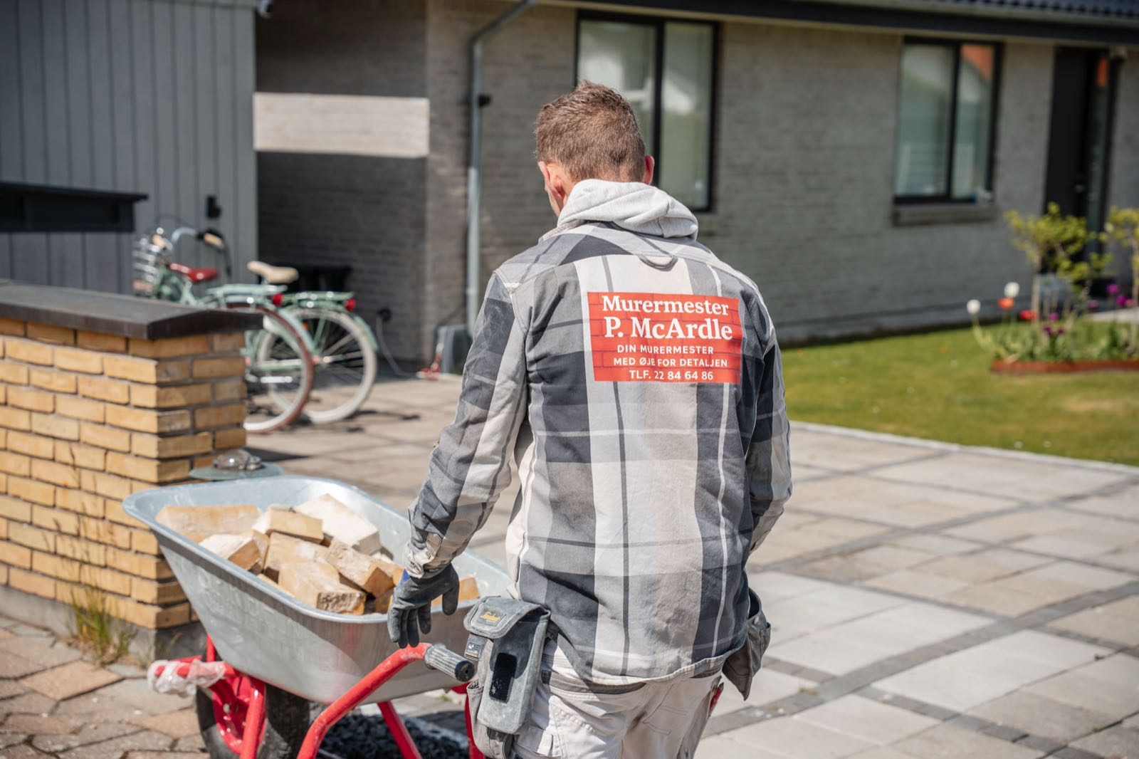 Murermester kører trillebør med sten til en udendørs opgave