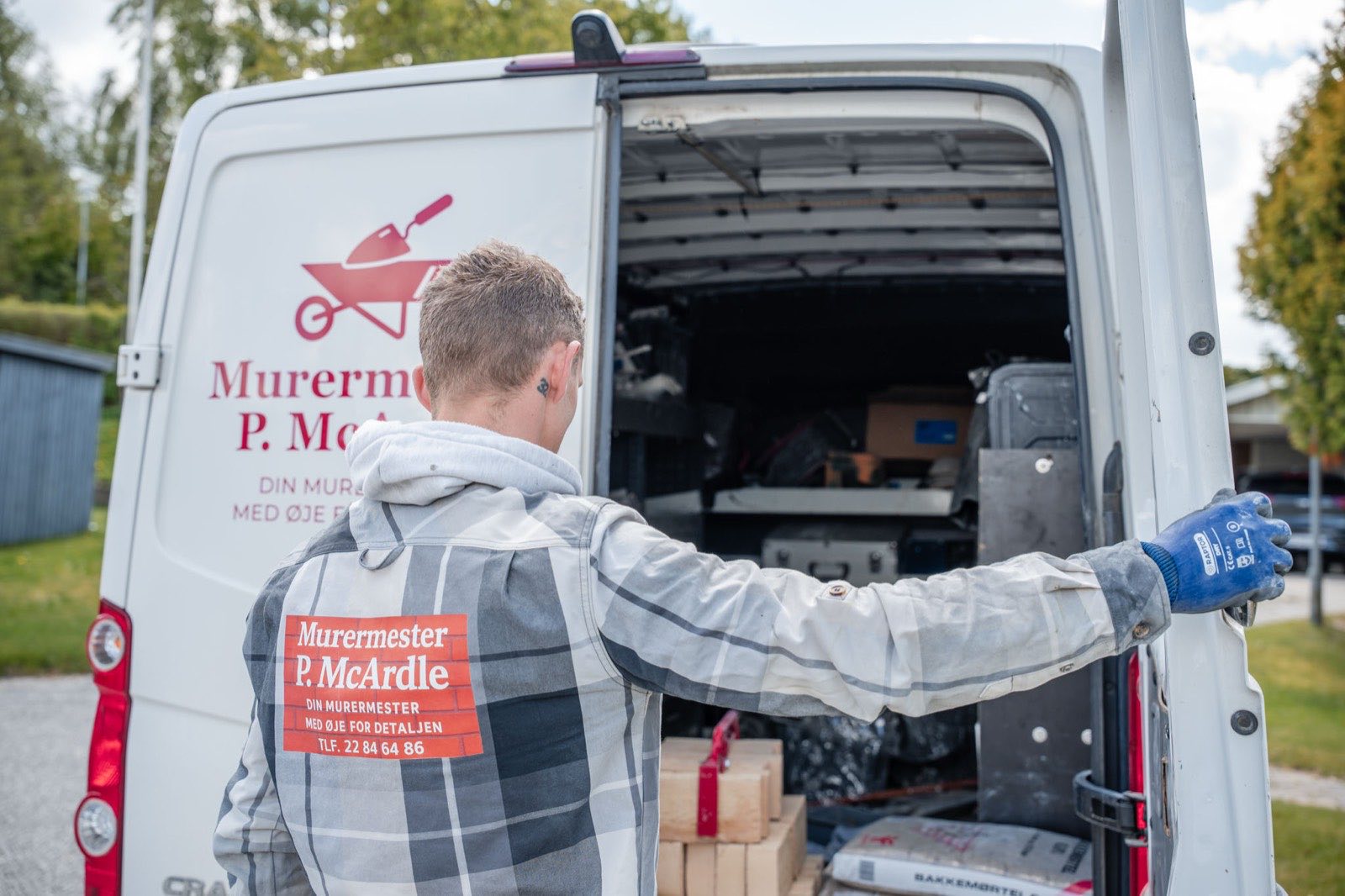 Murermester ved den åbne varevogn med værktøj og materialer